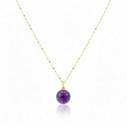 Necklace with a purple bead pendant on a gold chain against a white background