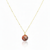 Necklace with a round, multicolored pendant on a thin chain against a white background