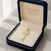 Gold key-shaped pendant in a 'Embellish Gold Jewelry & Diamond' box on a neutral background