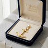 Gold anchor pendant in a 'Embellish Gold Jewelry & Diamond' box on a light background