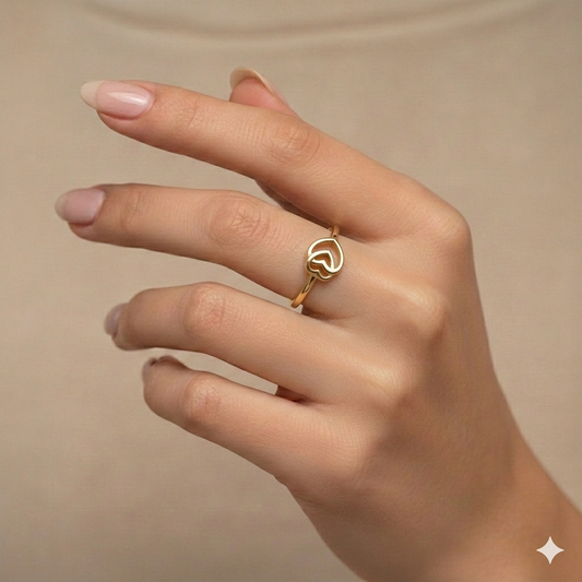 Gold ring on a hand against a beige background