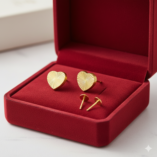 Gold heart-shaped stud earrings in a red jewelry box, elegant gold jewelry design