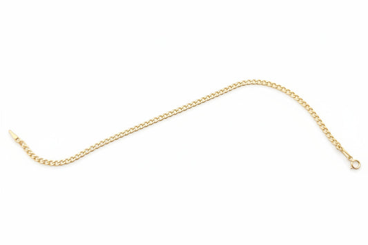 Gold chain on a black surface with a visible brand label.