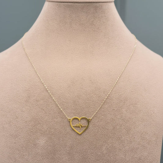 Gold necklace with a heart-shaped pendant on a mannequin.