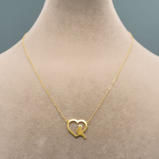Gold necklace with a heart-shaped pendant on a mannequin.