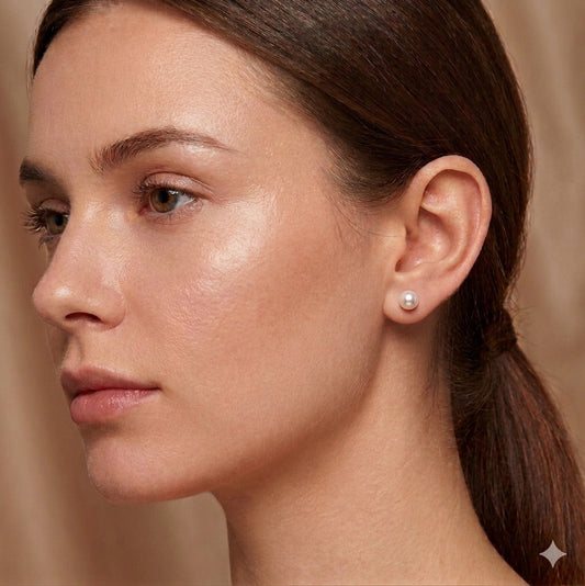 Close-up of a woman wearing a pearl earring against a neutral background