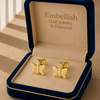 Gold butterfly earrings in a 'Embellish Gold Jewelry & Diamond' box on a wooden surface.