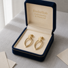 Gold earrings in a 'Embellish Gold Jewelry & Diamond' box on a light surface.