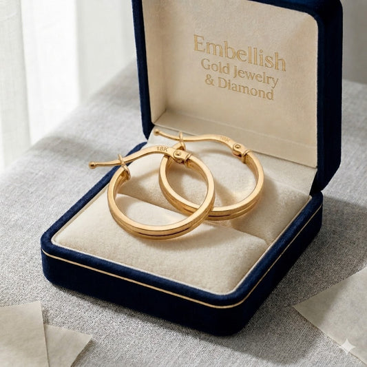 Gold hoop earrings in a 'Embellish Gold Jewelry & Diamond' box on a textured surface.