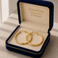 Gold hoop earrings in a 'Embellish Gold Jewelry & Diamond' box on a textured surface.