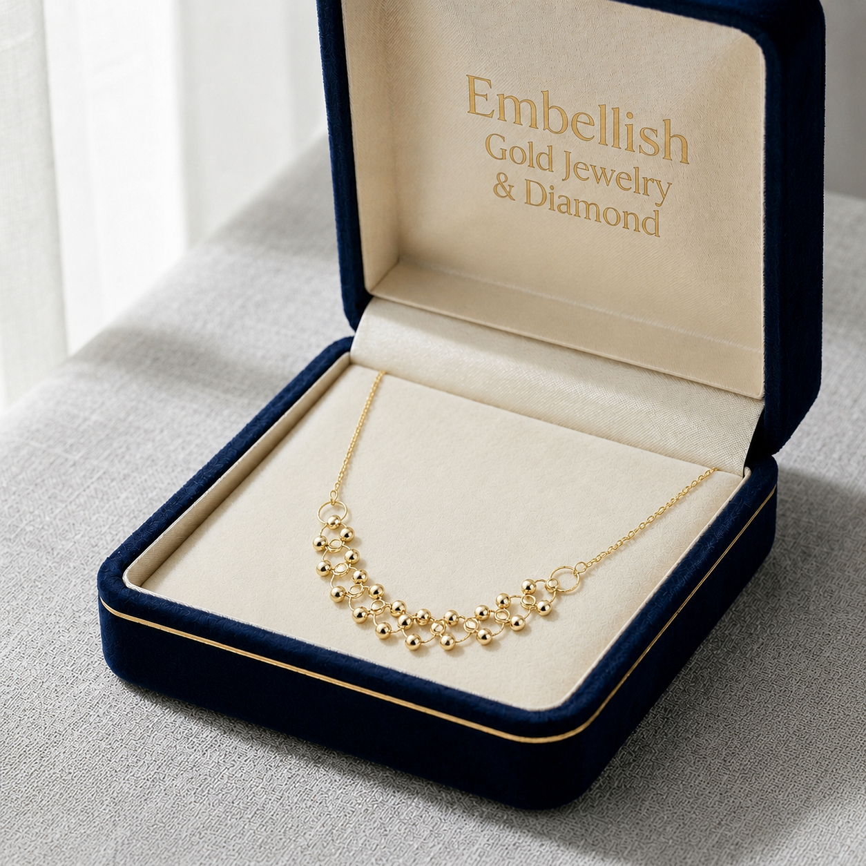 Gold necklace in an open jewelry box with 'Embellish Gold Jewelry & Diamond' branding.