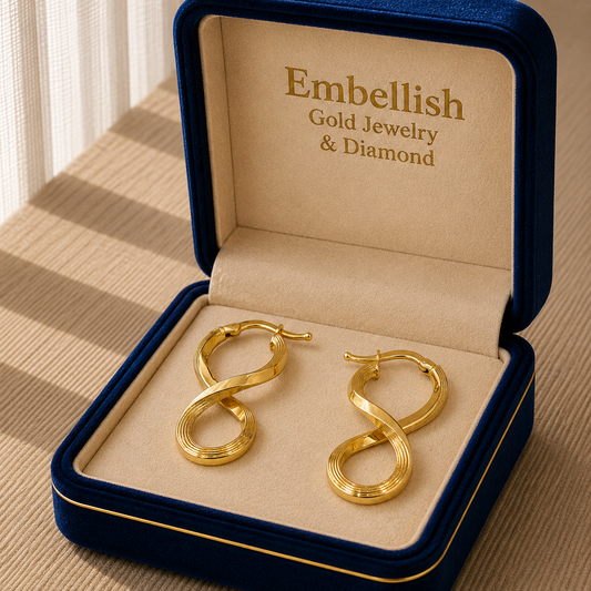 Gold hoop earrings in a 'Embellish Gold Jewelry & Diamond' box on a beige surface.