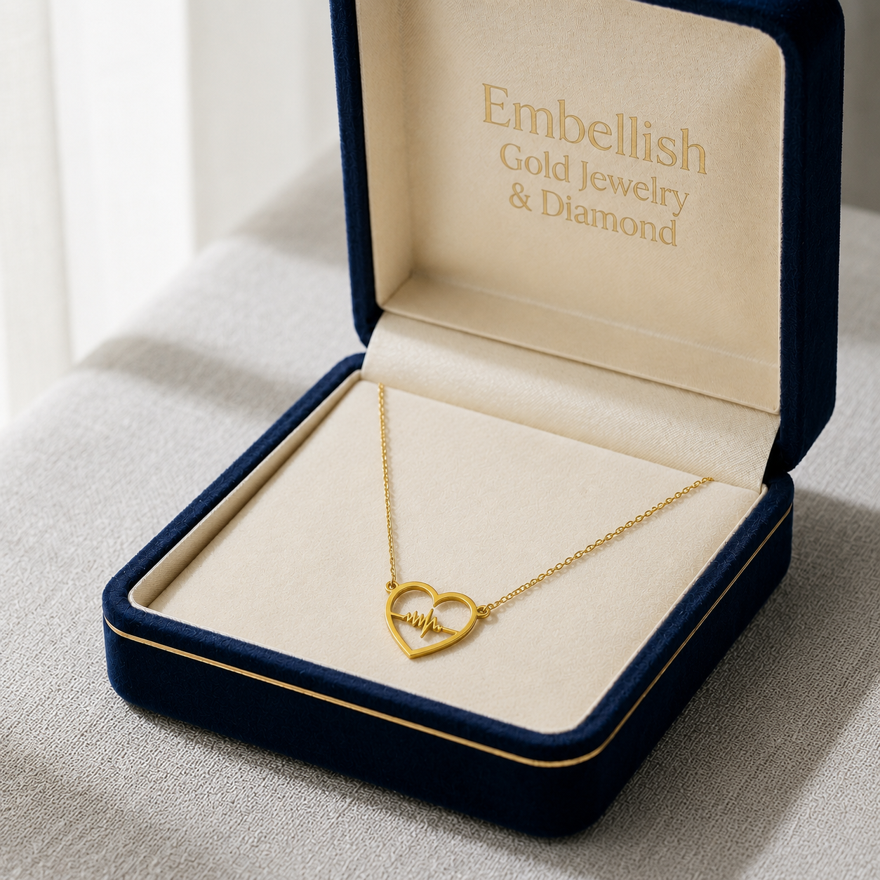 Gold necklace with heart design in an open jewelry box labeled 'Embellish Gold Jewelry & Diamond'.