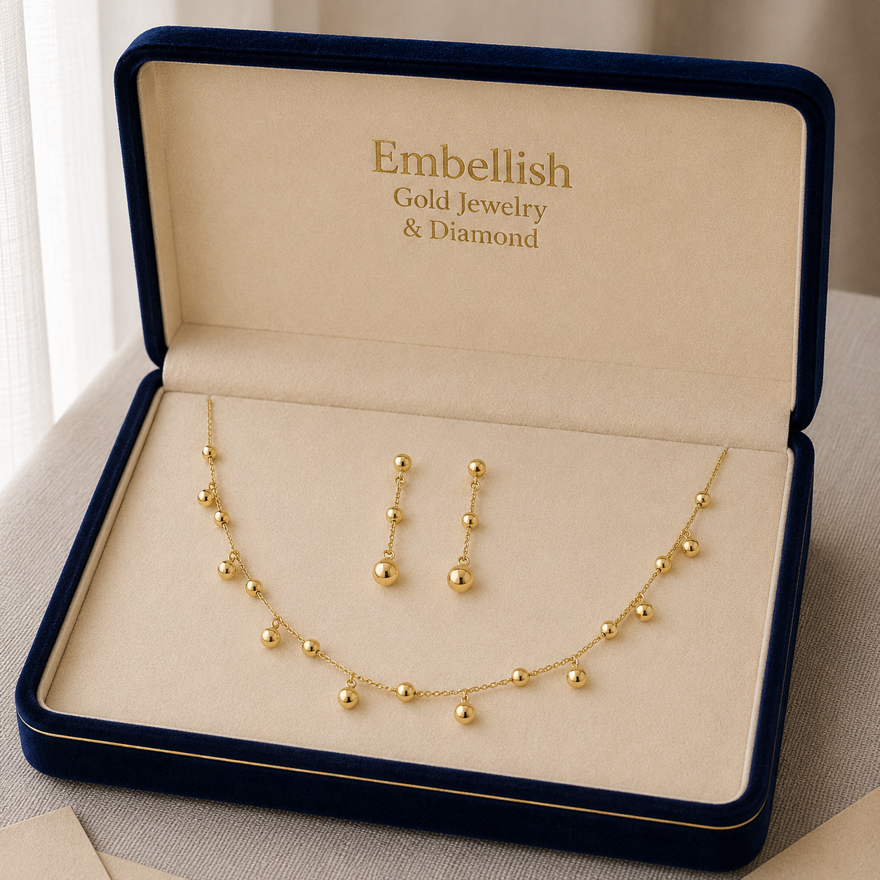 Gold jewelry set including necklace and earrings in an 'Embellish' box.