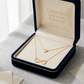 Gold necklace with heart and infinity designs in a 'Embellish Gold Jewelry & Diamond' box.