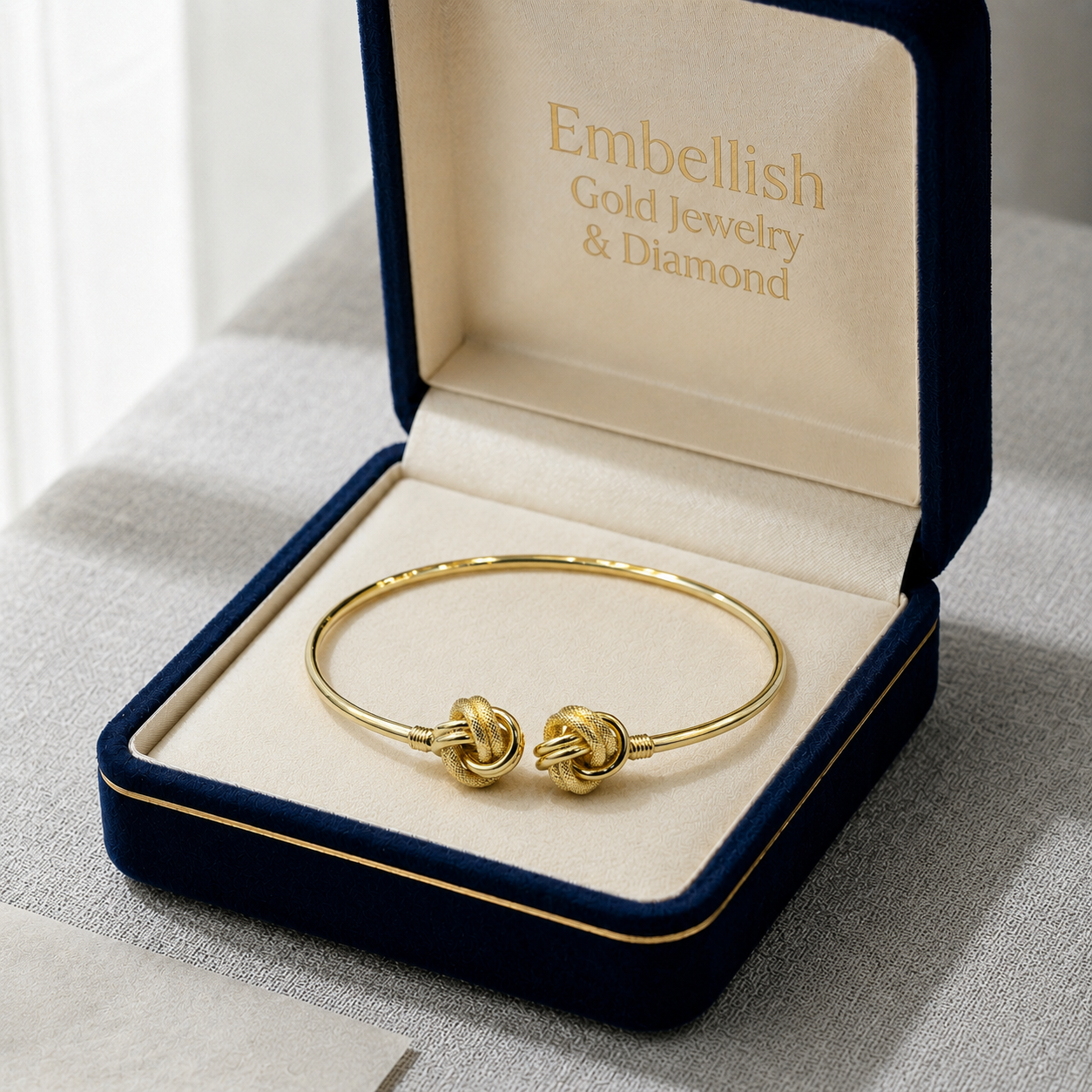 Gold bracelet in a 'Embellish Gold Jewelry & Diamond' box on a light gray surface.