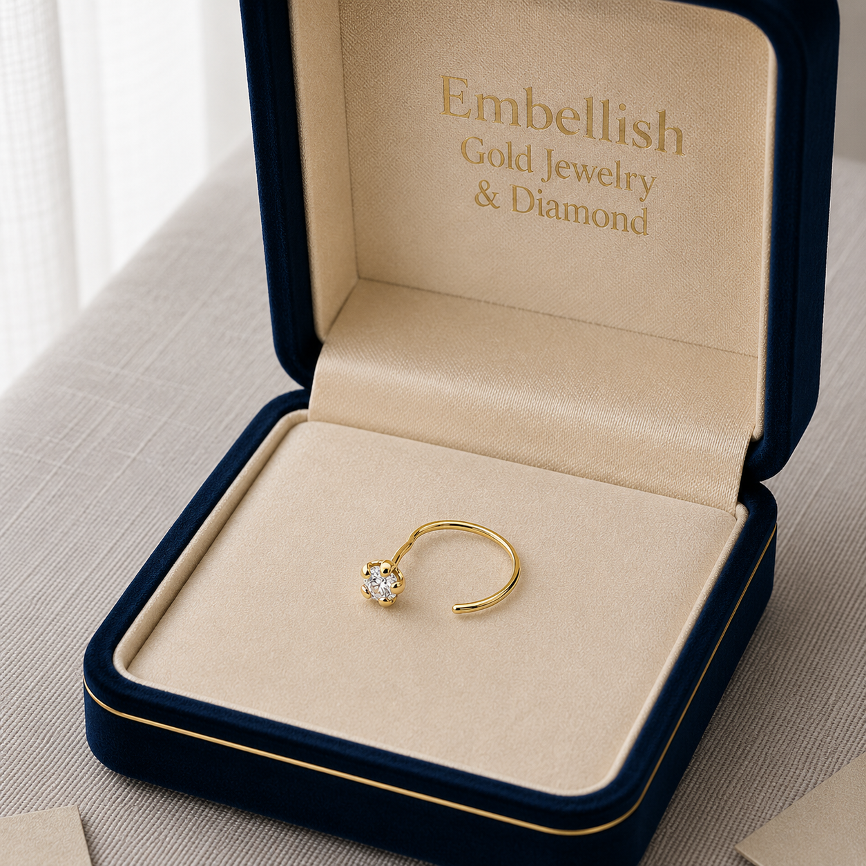 Gold ring in a 'Embellish Gold Jewelry & Diamond' box on a neutral background