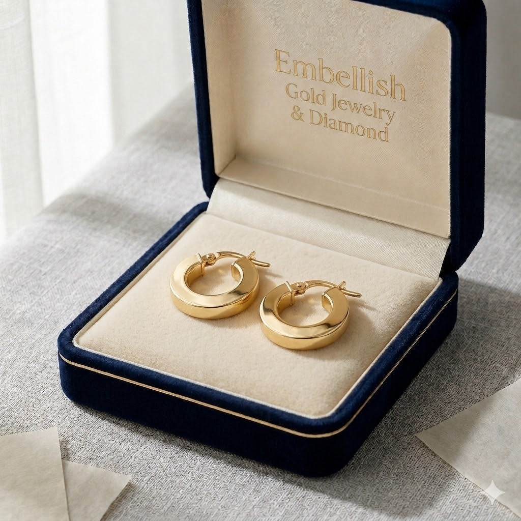 Gold hoop earrings in a 'Embellish Gold Jewelry & Diamond' box on a textured surface.