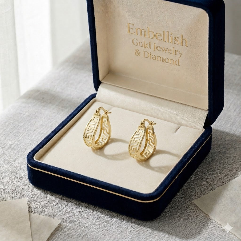Gold earrings in a 'Embellish Gold Jewelry & Diamond' box on a textured surface.