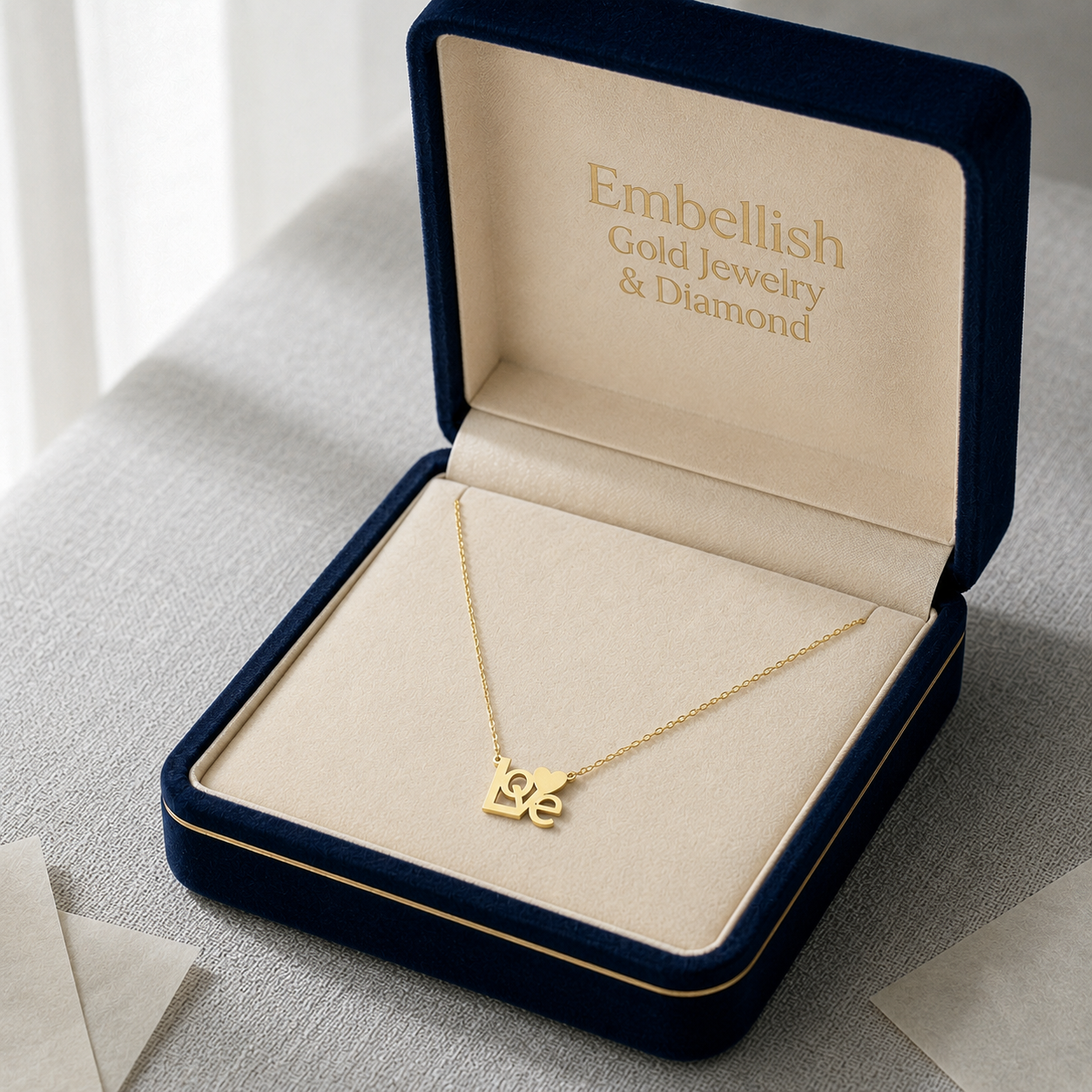 Gold necklace with 'LOVE' pendant in a 'Embellish Gold Jewelry & Diamond' box.