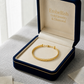 Gold bracelet in an open jewelry box with 'Embellish Gold Jewelry & Diamond' branding.