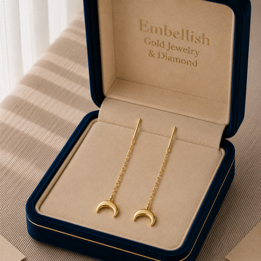 Gold moon-shaped earrings in a 'Embellish' jewelry box.