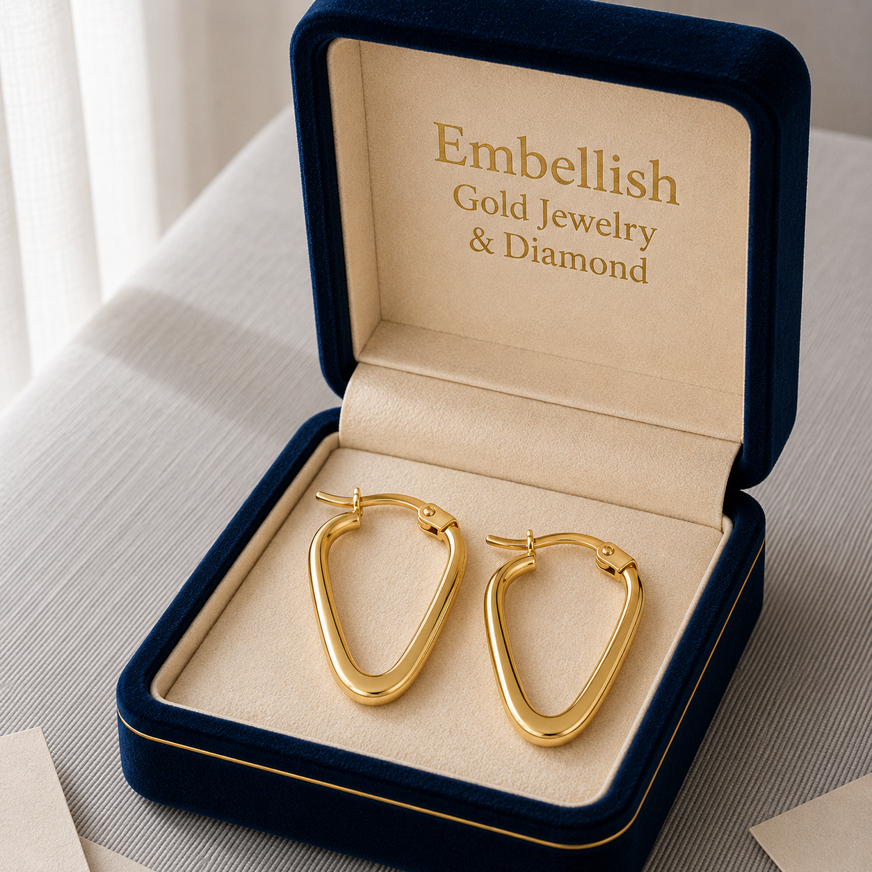 Gold hoop earrings in a 'Embellish Gold Jewelry & Diamond' box.