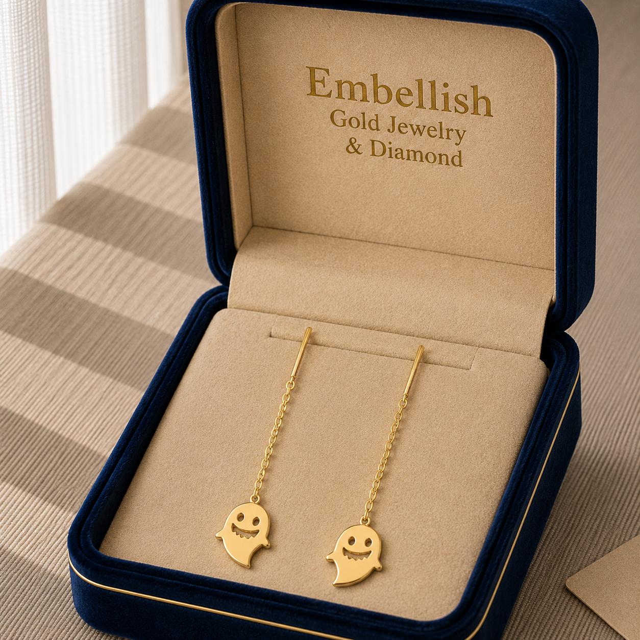 Gold ghost-shaped earrings in a 'Embellish Gold Jewelry & Diamond' box.