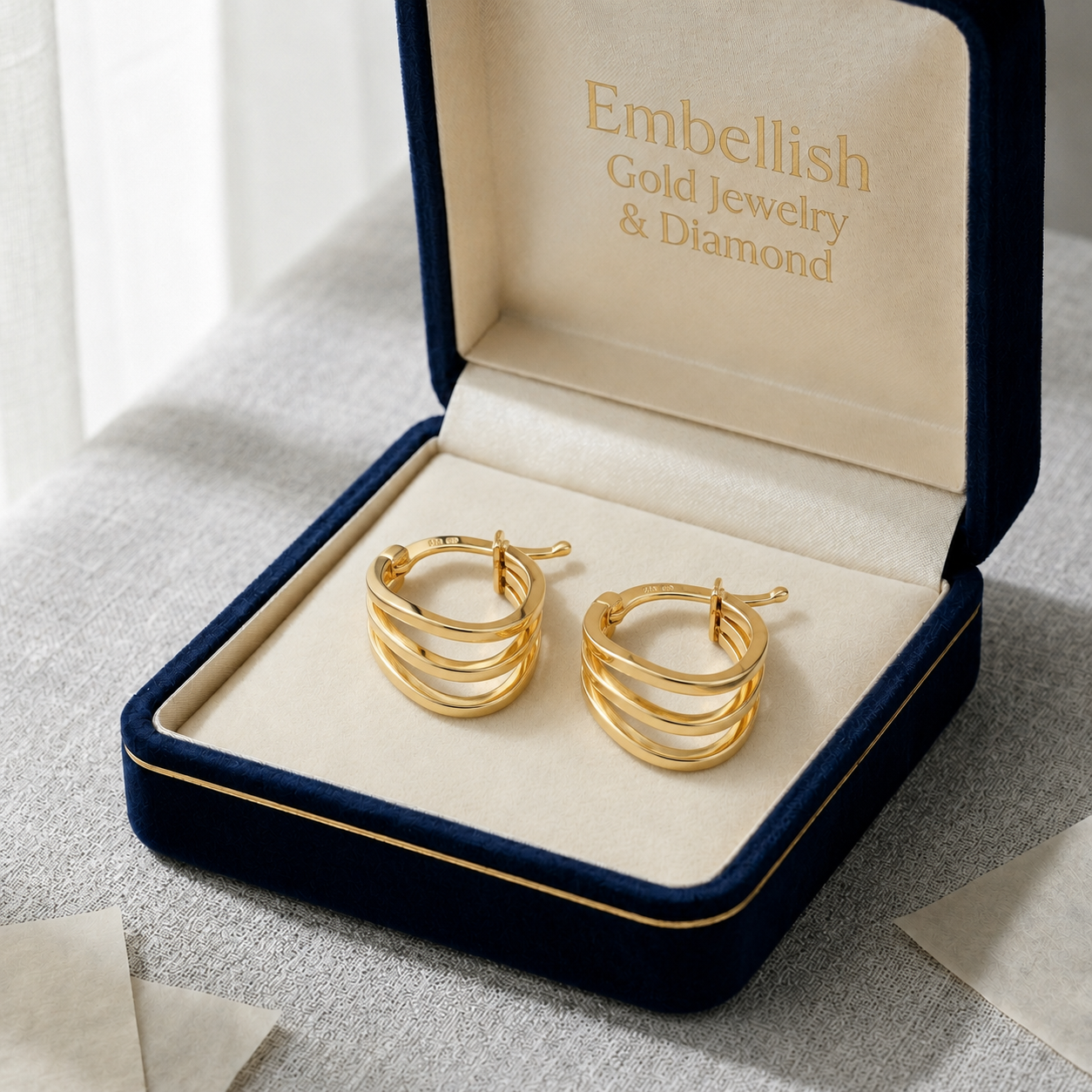 Gold hoop earrings in a 'Embellish Gold Jewelry & Diamond' box on a light background