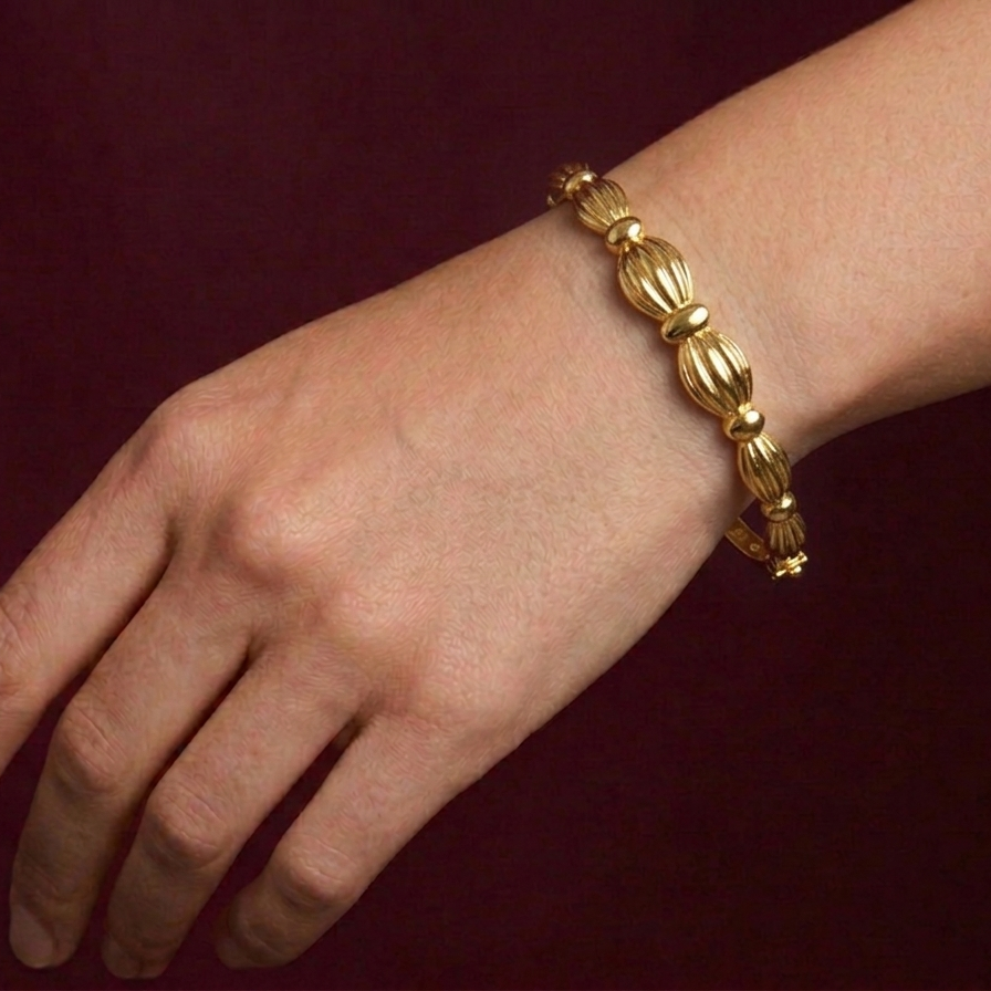 Gold bracelet on a wrist against a dark red background