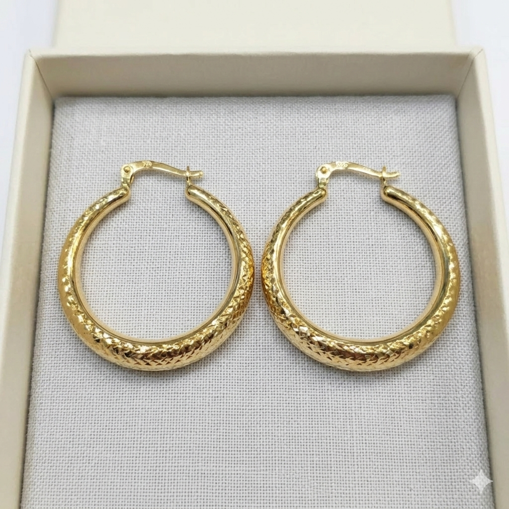 Gold hoop earrings on a gray fabric surface
