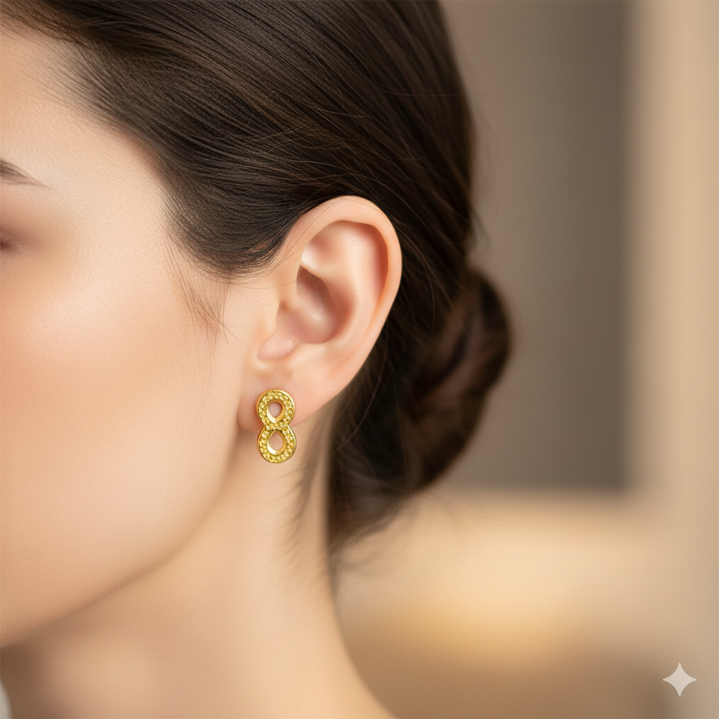 Close-up of a woman's ear wearing gold infinity stud earring, elegant jewelry style