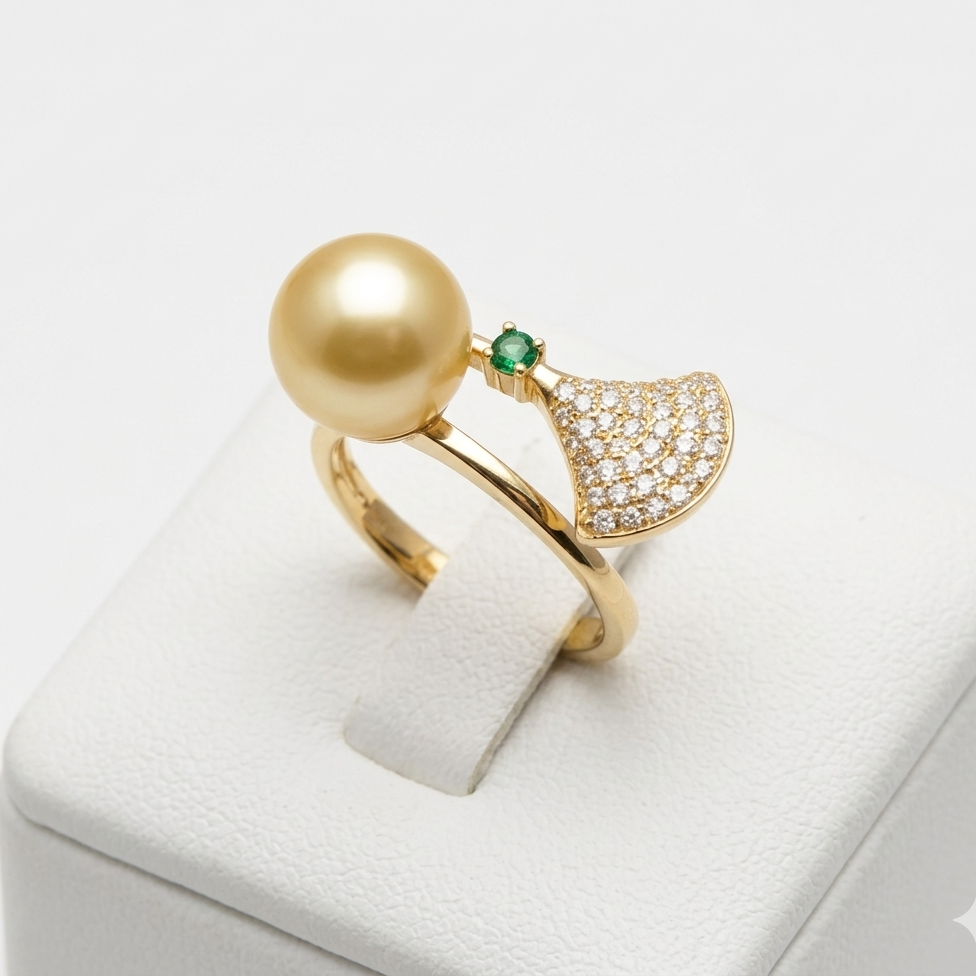 Gold ring with a large pearl and green gemstone on a white stand