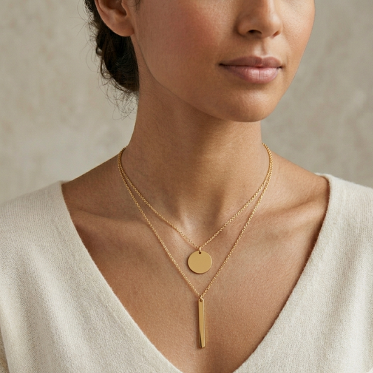 Woman wearing a gold necklace with a heart-shaped pendant against a neutral background