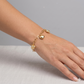 Gold bracelet with heart charms on a wrist against a neutral background