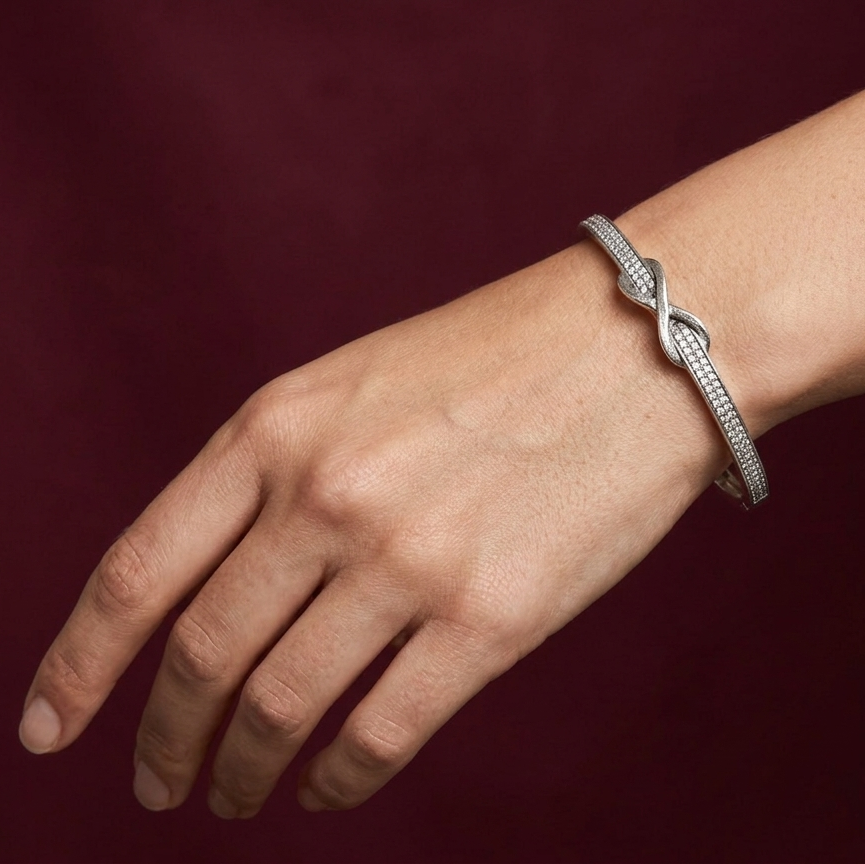 Silver bracelet on a wrist against a dark red background