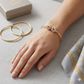 Gold bracelet on a hand with gold rings and a box in the background