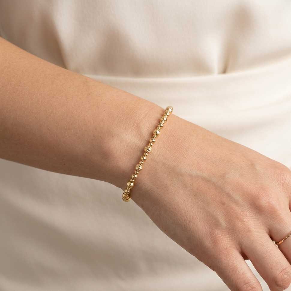 Gold bracelet on a person's wrist against a neutral background