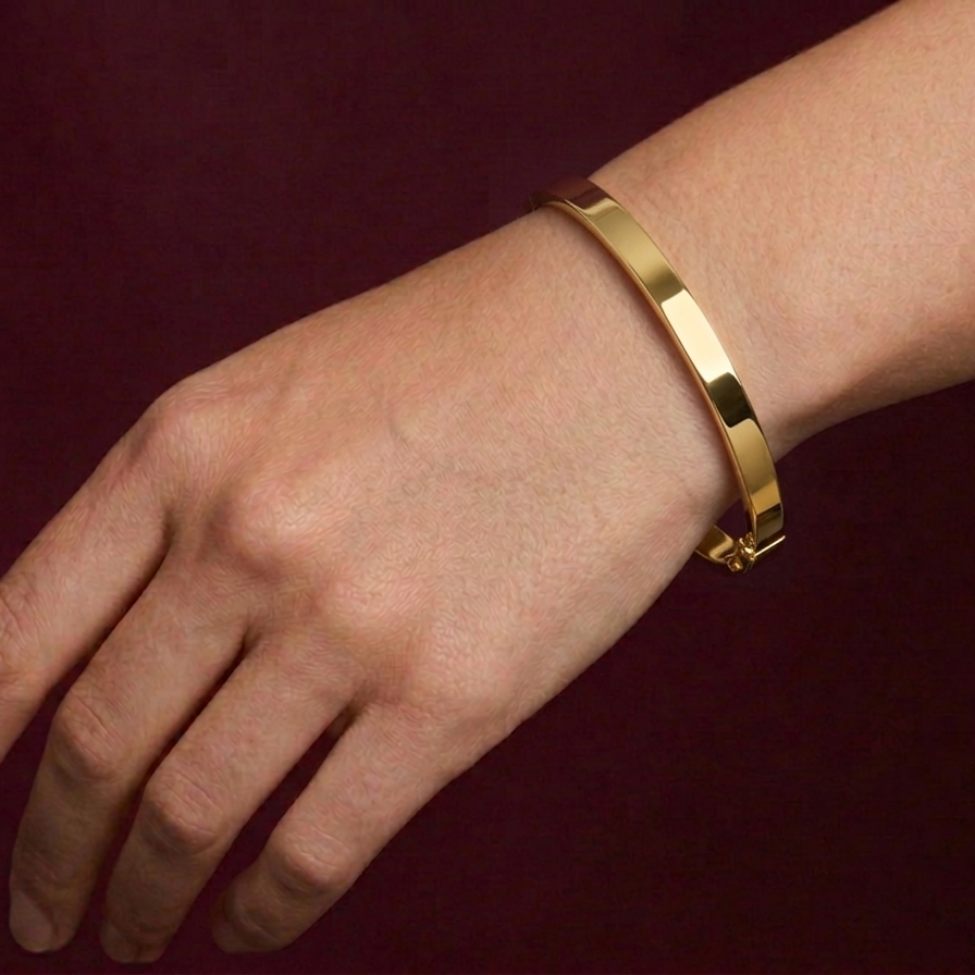 Gold bracelet on a wrist against a dark background
