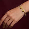 Gold butterfly bracelet on a wrist against a dark background