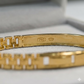Gold bracelet with hallmark on a light gray background
