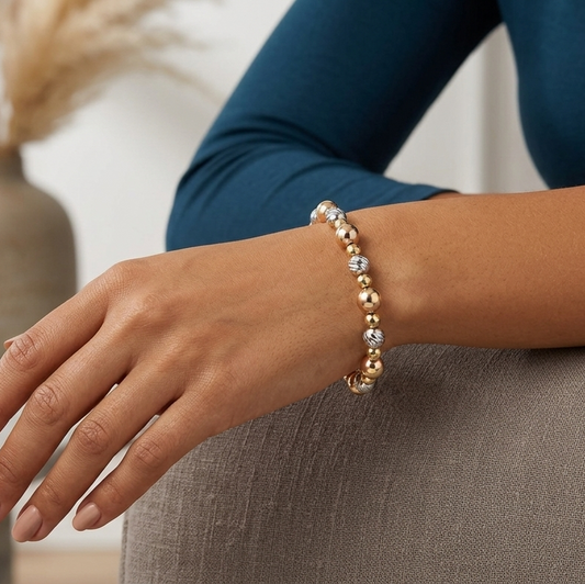 Person wearing a gold bracelet on a blurred indoor background