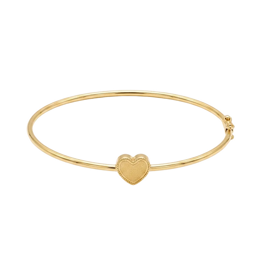 Gold bangle with a heart charm on a white background
