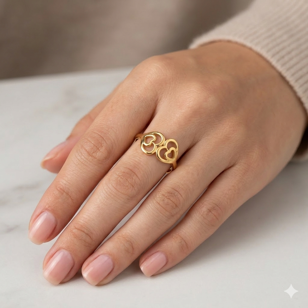 Gold ring with heart design on a hand against a neutral background