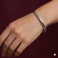Silver bracelet on a wrist against a dark red background