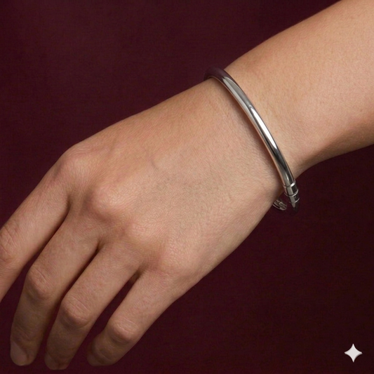 Silver bracelet on a wrist against a dark red background