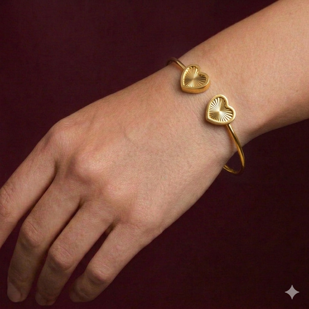 Gold bracelet with heart-shaped ends on a wrist against a dark red background