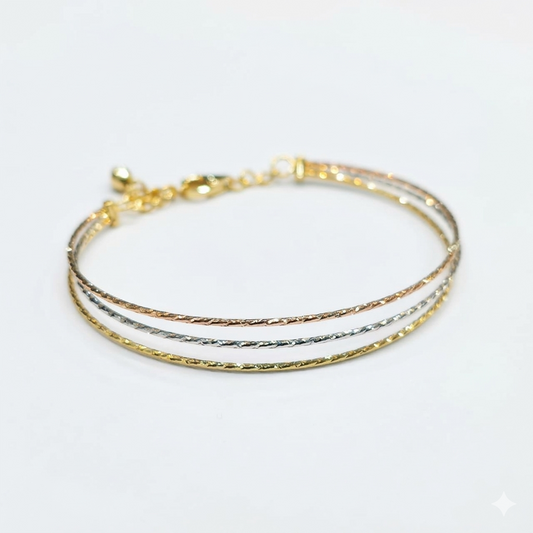 Three gold bracelets stacked on a white background