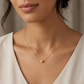 Close-up of a woman wearing a gold necklace with a heart pendant.
