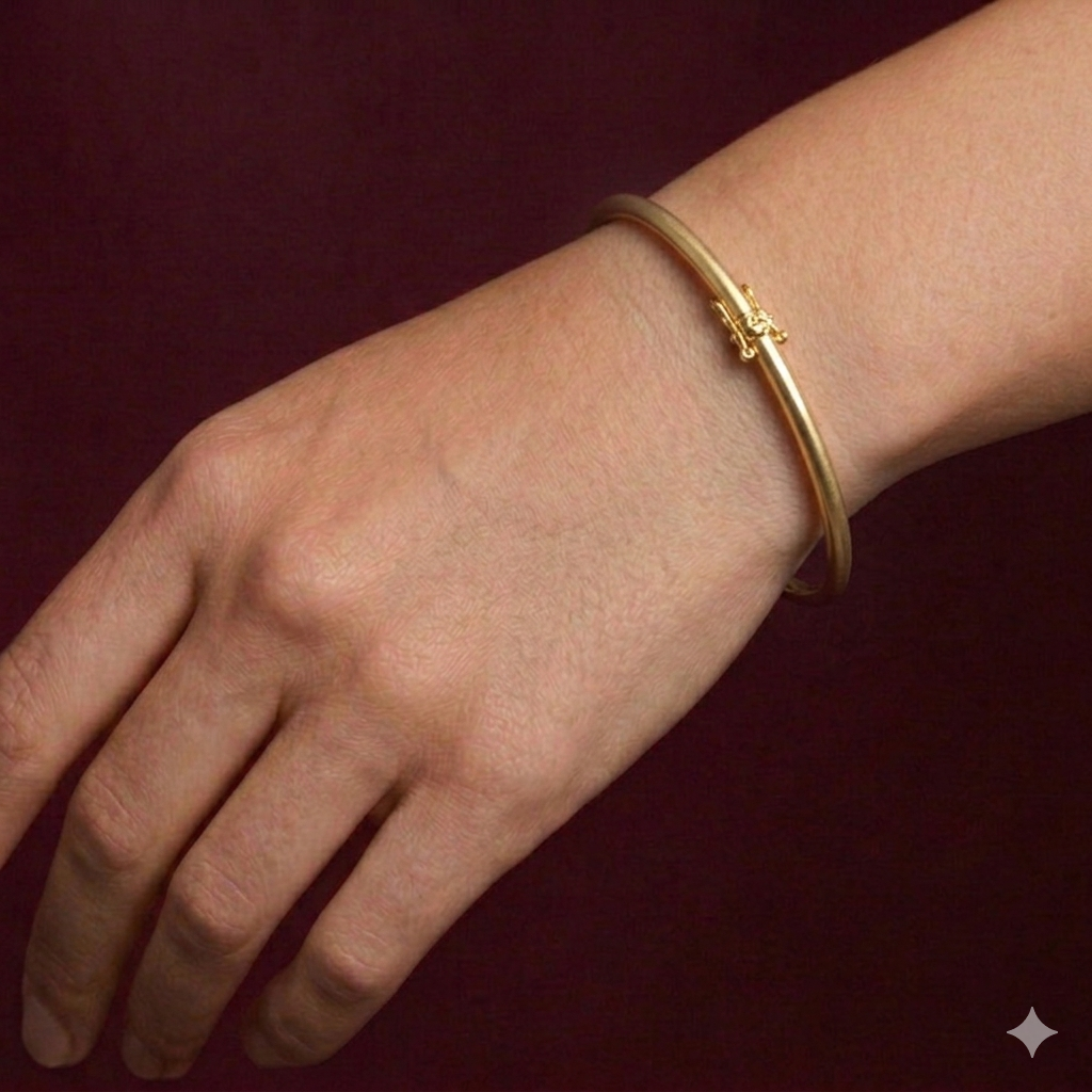 Gold bracelet on a wrist against a dark red background